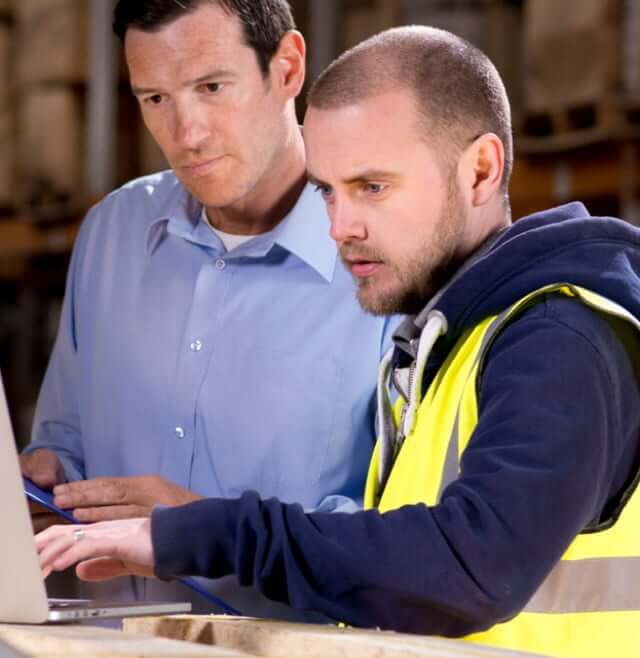 Two men looking at a computer monitor together.